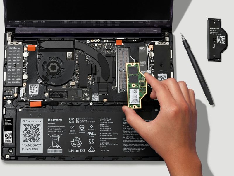 Nyitott Framework Laptop 13 Pro, kézben tartott LPCAMM2 memóriamodullal.