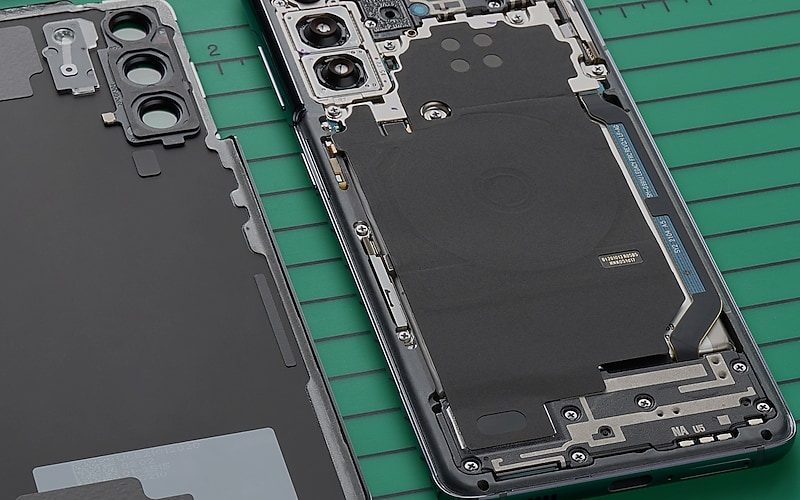 Felnyitott Samsung Galaxy telefon és hátlap zöld javítószőnyegen.