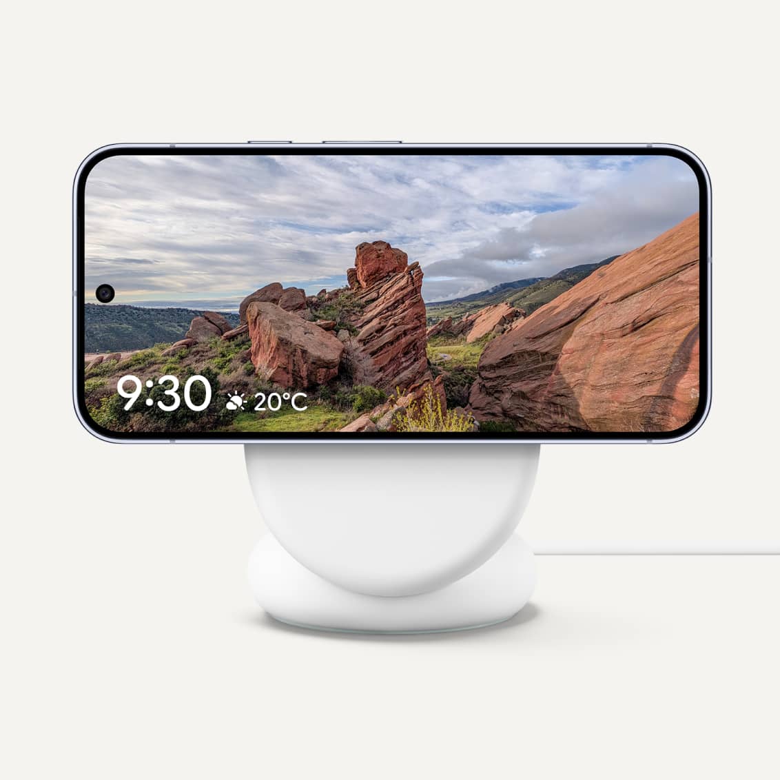 Pixel telefon fekvő helyzetben egy fehér Google Pixelsnap töltőállványon.