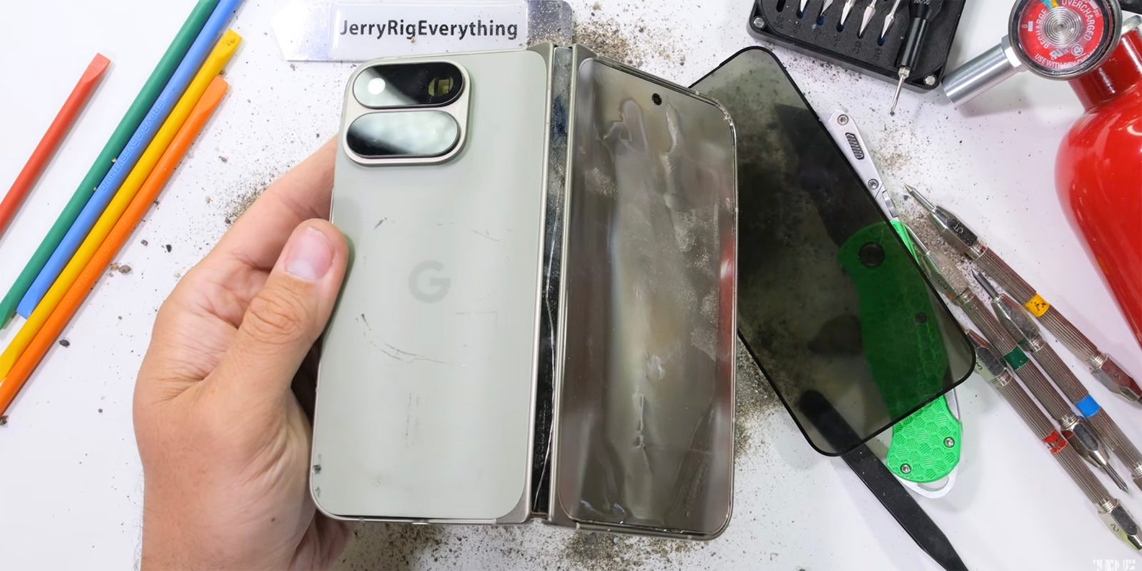 Sérült Pixel 11 Pro Fold a JerryRigEverything tesztasztalán, a levált előlapi panel mellett.