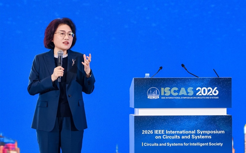 He Tingbo mikrofonnal beszél az ISCAS 2026 konferencián, kék háttér és konferenciapulpitus előtt.